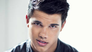 Taylor Lautner Smirking At The Camera With Confidence Wallpaper