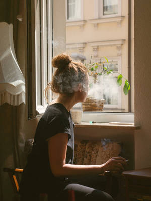 Teenage Girl Sitting And Smoking On A Window Wallpaper