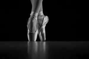 The Elegance Of Ballet: Gleaming Pointe Shoes In The Darkness Wallpaper