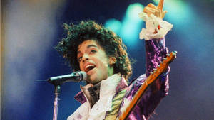The Iconic Singer, Prince Playing A Guitar On Stage Wallpaper