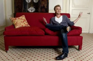 Tom Felton On Red Couch Wallpaper