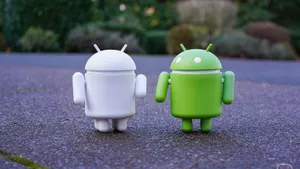 Two Android Toys Standing Next To Each Other Wallpaper