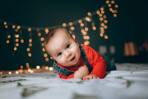 Very Cute Baby With Christmas Lights Wallpaper