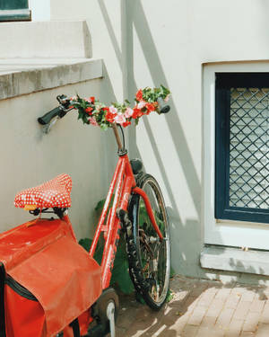 Vibrant Red Bike Adorned With Fresh Flowers Wallpaper