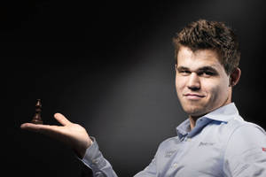 World Chess Champion Magnus Carlsen Holding A Black Bishop Wallpaper